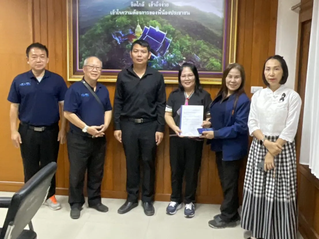 ทีม NICH TEC กับเจ้าหน้าที่หน่วยงาน ถือเอกสารร่วมกันในห้องประชุมของหน่วยงาน